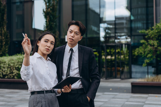 Asian colleagues analyze digital business data about environment meeting near company building