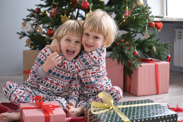 cute kids in Christmas pajamas with gift boxes at christmas morning