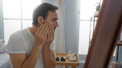Man examining face in spa room with serene atmosphere and soft lighting, showcasing mature beauty and wellness focus in an indoor salon setting.