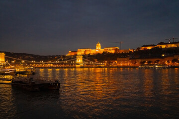 A photo of a boat is on the water in front of a bridge