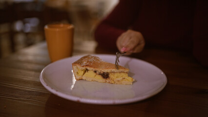 A young woman enjoys a delicious slice of cake at an indoor italian restaurant.