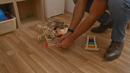 Man kneeling in living room organizing toys including a stuffed giraffe and colorful xylophone on...