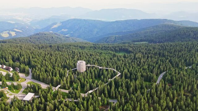 Aerial view of a serene forest and treetop trail with a view tower amidst lush greenery, Rogla, Slovenia.