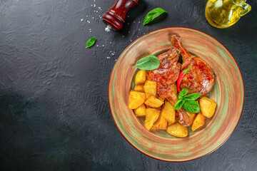roasted duck leg with potatoes on a dark background. top view. copy space for text