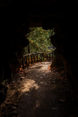 A photo of a dirt path through a cave with a light coming through the cave