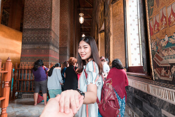 Fototapeta premium Beautiful tourist asian women leading man hand go to travel together in buddhist temple