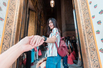 Beautiful tourist asian women leading man hand go to travel together in buddhist temple