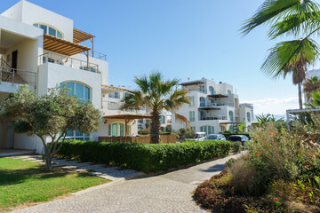 Fototapeta premium Charming coastal villas along a sunlit pathway in a serene seaside community.