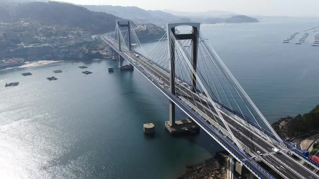 Aerial view of the majestic Rande Bridge spanning the river with a beautiful landscape of mountains and clear sky, Redondela, Spain.