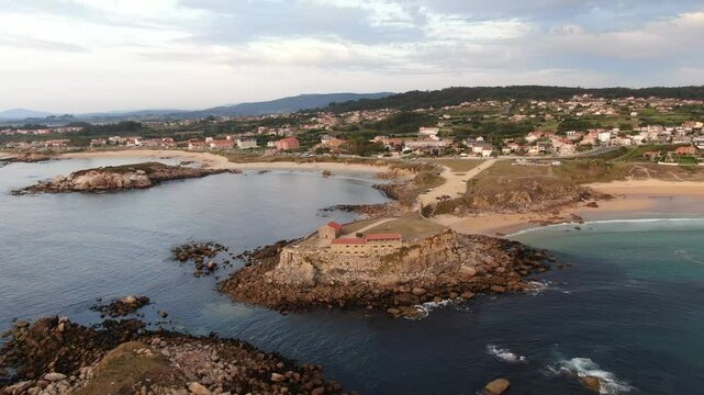 Aerial view of Ermida da Lanzada with sandy beach and rocky coastline, Sanxenxo, Galicia, Spain.