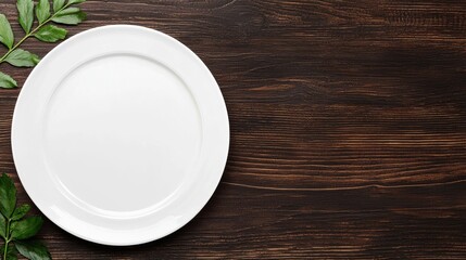 Empty white plate on a wooden table, surrounded by fresh greenery. Ideal for food presentation or decorative culinary themes.