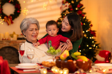Grandmother, mother and little boy celebrate happily on Christmas night