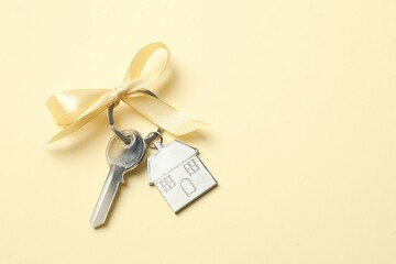 Metallic key with keychain in shape of house on color background