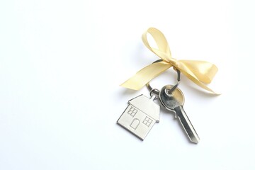 Metallic key with keychain in shape of house on white background