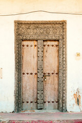 A Swahili door or Zanzibar door on the entrance of the Old Fort - An abandoned historical building in Old Stone Town, Bagamoyo, Tanzania
