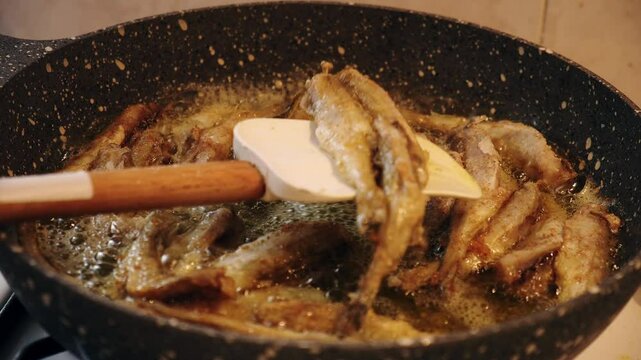 The cook turns the black sea haddock fishes in a granite pan in 2x slow motion