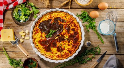 Homemade traditional quiche lorraine with ham and cheese on wooden background