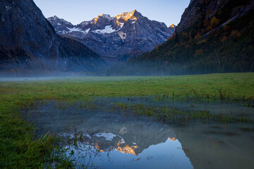 mountain lake during sunrise with the reflection of mountains at the alps of austria in autumn