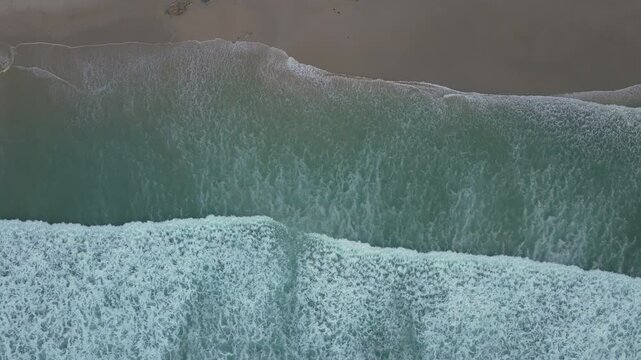 Drone shot of Foamy Sea Waves On Thesandy  Beach In Caion, A Laracha, Spain