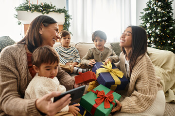 Family members share laughter and joy while unwrapping colorful gifts by their beautifully decorated tree.