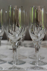 Close-up of multiple empty champagne glasses arranged in rows, showcasing their elegant curves and reflections, ready for a celebration. Blurred background adds depth.