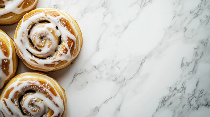 Fototapeta premium Freshly baked cinnamon rolls with icing on a marble countertop in a cozy kitchen setting