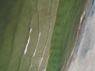 Aerial View of Coastal Interaction Between Sea and Beach Creating Natural Textures