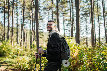 Young caucasian man hiking or trekking through the forest	