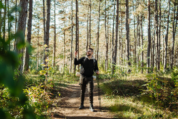 Fototapeta premium Young caucasian man hiking or trekking through the forest 