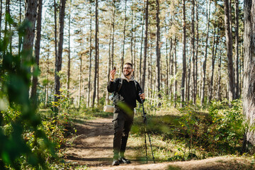 Young caucasian man hiking or trekking through the forest	