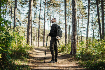 Obraz premium Young caucasian man hiking or trekking through the forest 