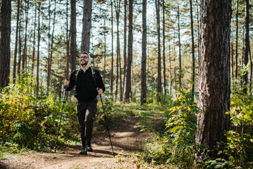 Fototapeta premium Young caucasian man hiking or trekking through the forest 