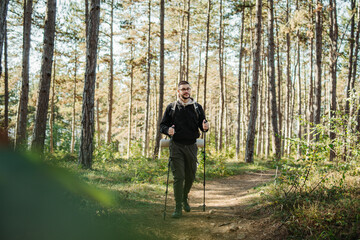 Young caucasian man hiking or trekking through the forest	