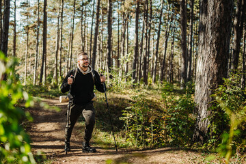 Young caucasian man hiking or trekking through the forest	