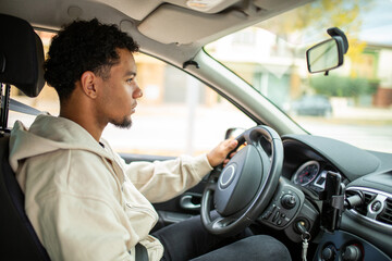 Focused man driving car with one hand on steering wheel