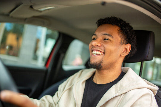 Man smiling while driving a car in urban environment