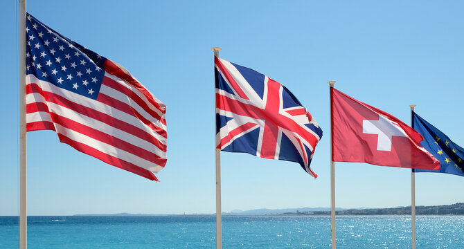 The flags of the United States, Great Britain, Switzerland, and the European Union in the wind at the coast of Nice, France