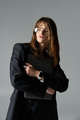 A fashionable young guy showcases his style while confidently holding a tablet in a sleek outfit.