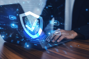 Man working on a laptop with advanced cyber security shield, ensuring the protection of sensitive...