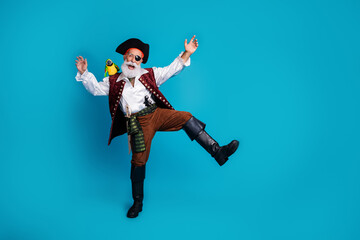 Photo of cheerful buccaneer man dressed pirate costume dancing isolated on blue color background