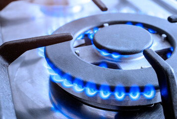 The gas burns in the burner of a kitchen stove
