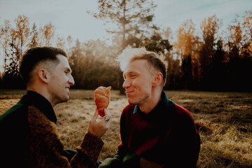 Obraz premium On a sunny autumn day, two friends have a picnic in the countryside. One friend feeds the other a croissant, and they enjoy each other's company. They feel happy and loved.