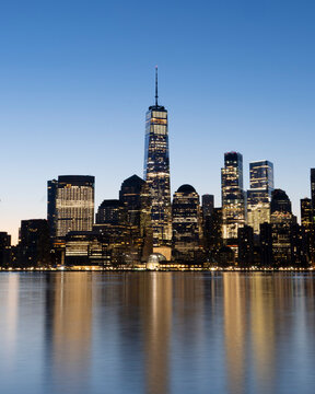 View of stunning new york city skyline with modern skyscrapers reflecting in the river at dusk, new york, united states of america.