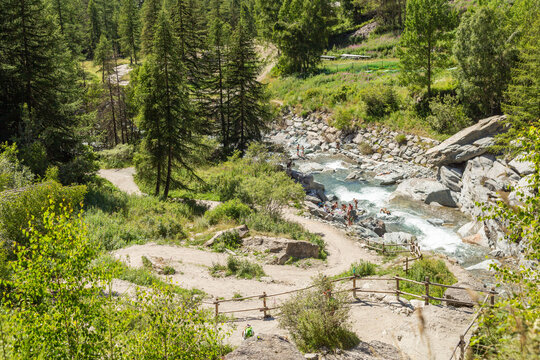View of serene Lilaz Waterfalls surrounded by lush forest and tranquil river, Cogne, Italy.