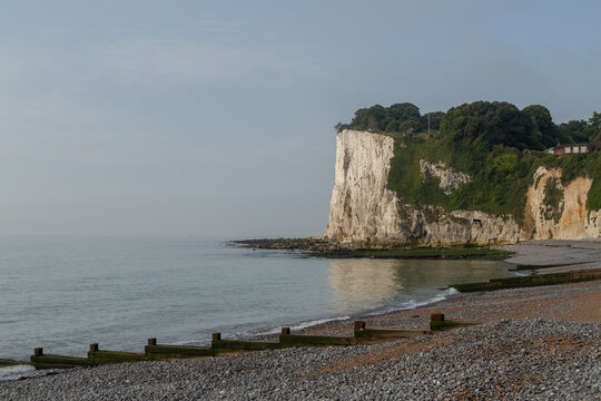 View of rugged cliffs and serene pebble beach by the calm sea, Dover, England.