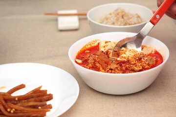 Lunch is ready, Homemade Soondubu Jjigae or spicy soft tofu stew, accompanied by a bowl of rice and a bowl of pickled white radish.
