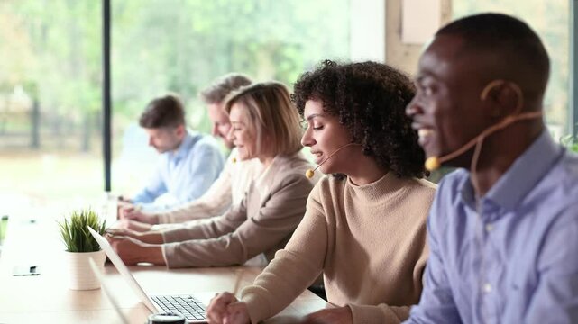 Diverse call center operators providing customer service with headsets and laptops