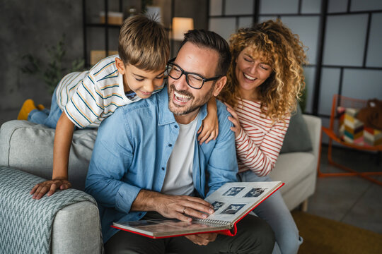mum, dad and son enjoy while look together family album with photos