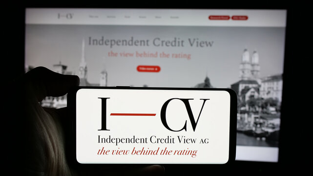 Stuttgart, Germany - 10-24-2024: Person holding smartphone with logo of rating agency Independent Credit View AG (I-CV) on screen in front of website. Focus on phone display.