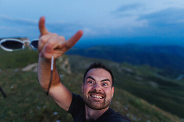 A man is capturing a selfie high up on a mountain, enjoying the beautiful view surrounding him...